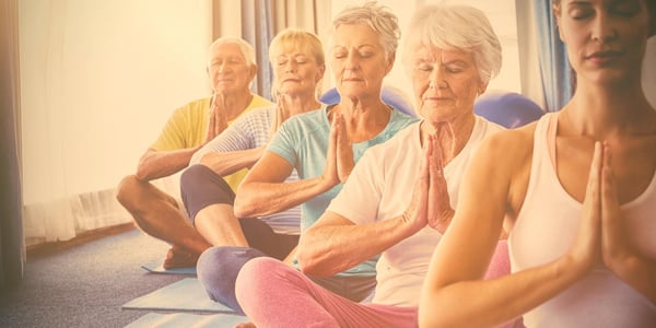 Elderly people with limited mobility doing yoga as a fun activity.